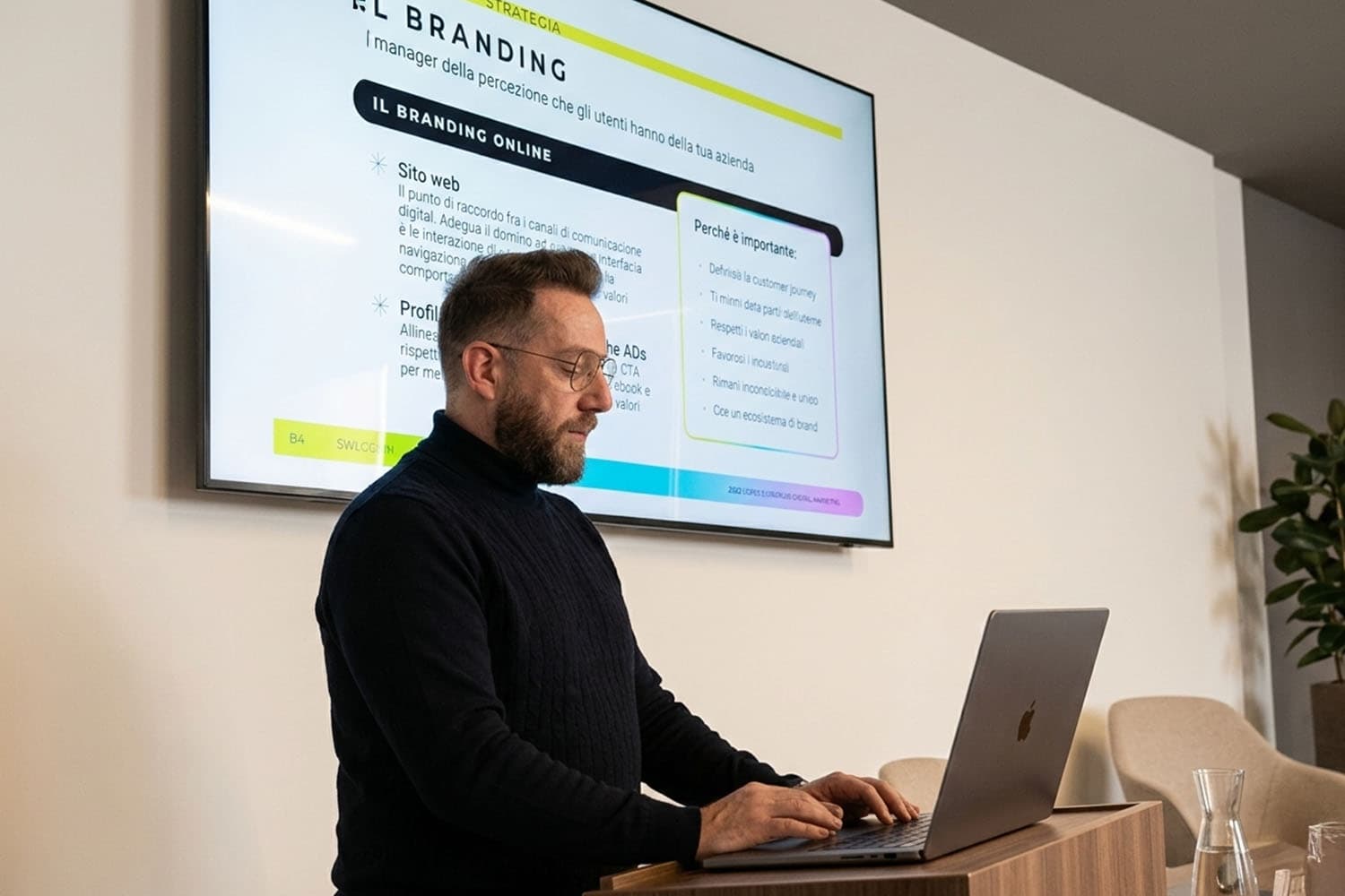 Un docente di SWI Academy illustra le slide sul branding online e la digital strategy durante un corso di formazione professionale, utilizzando un laptop.