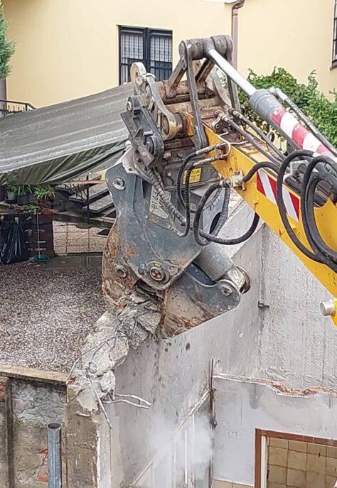 refort-demolizioni-fabbricati-e-ripristino-braccio-demolitore-con-frantumatore-orientabile-addenta-la-parte-alta-della-struttura-in-cemento